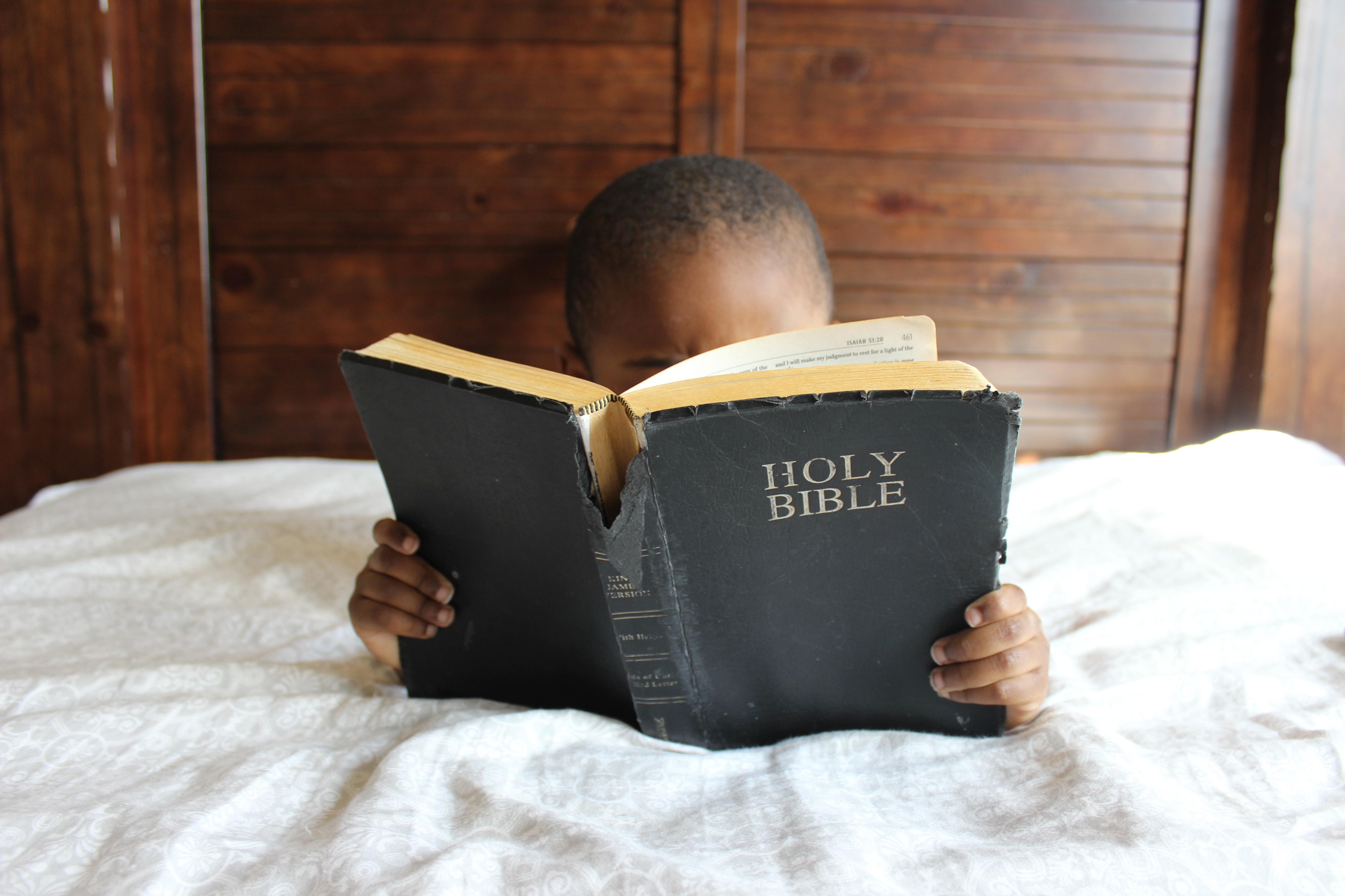 A child with his face hidden because the child is intently reading the bible